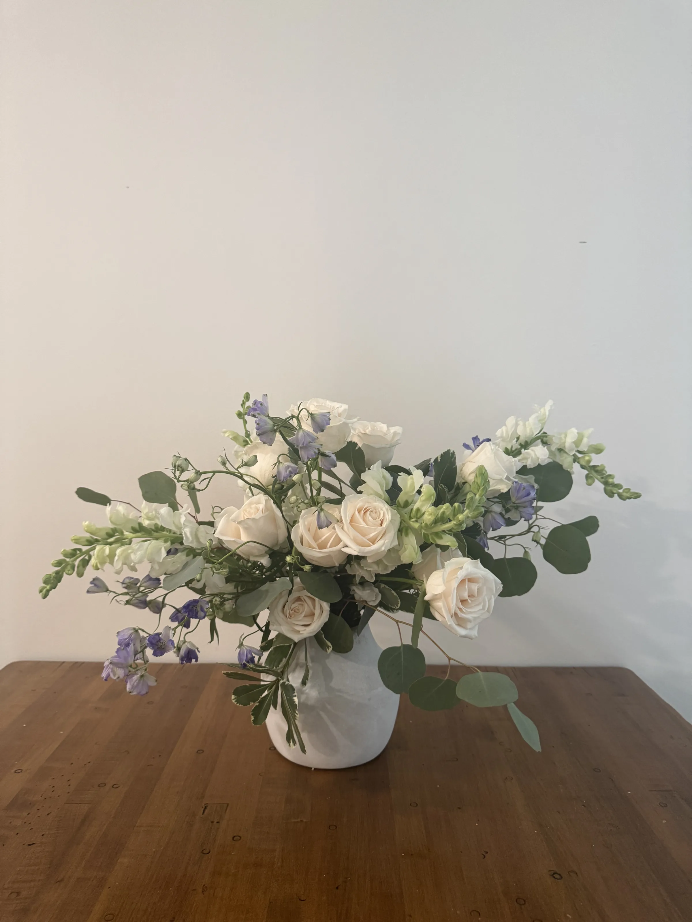 White rose, delphinium, and eucalyptus arrangement